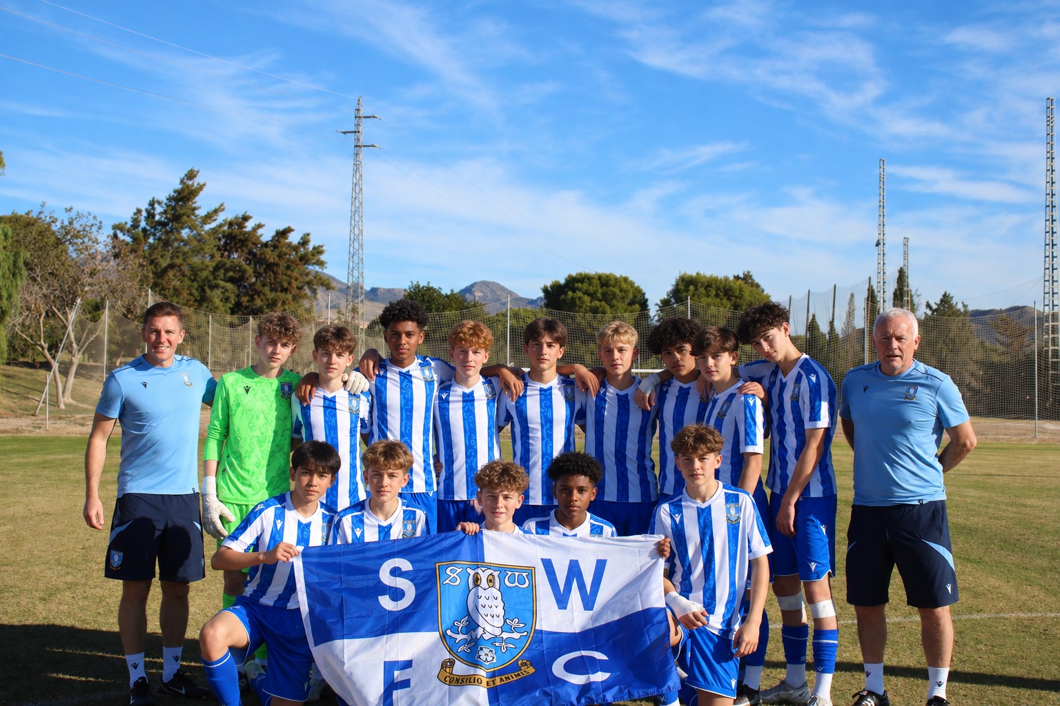 Junior squad posing for a team photo with their club flag