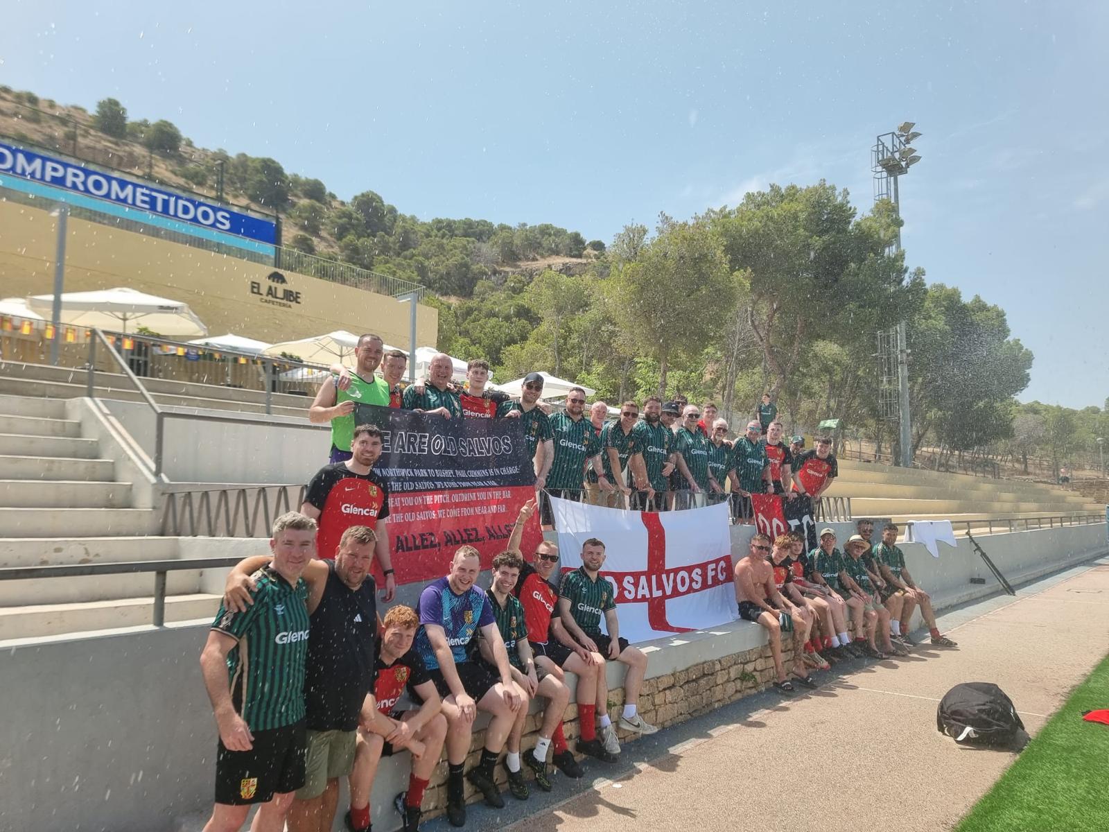 Adult touring team celebrating together at a Spanish football ground