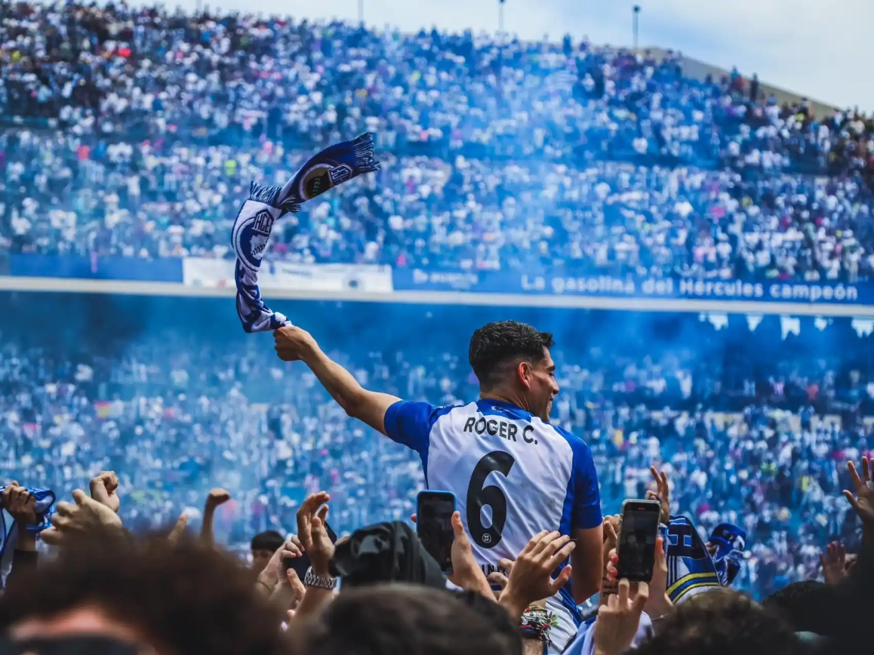 Hércules CF player Roger C. celebrates with fans and a club scarf at Estadio José Rico Pérez