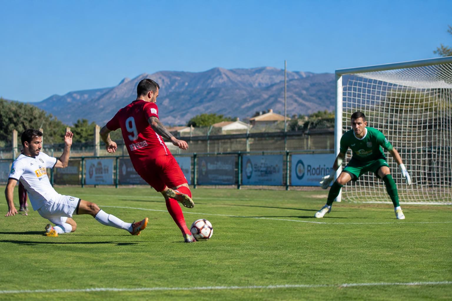Adult striker shooting at goal during a sunny match in Alicante