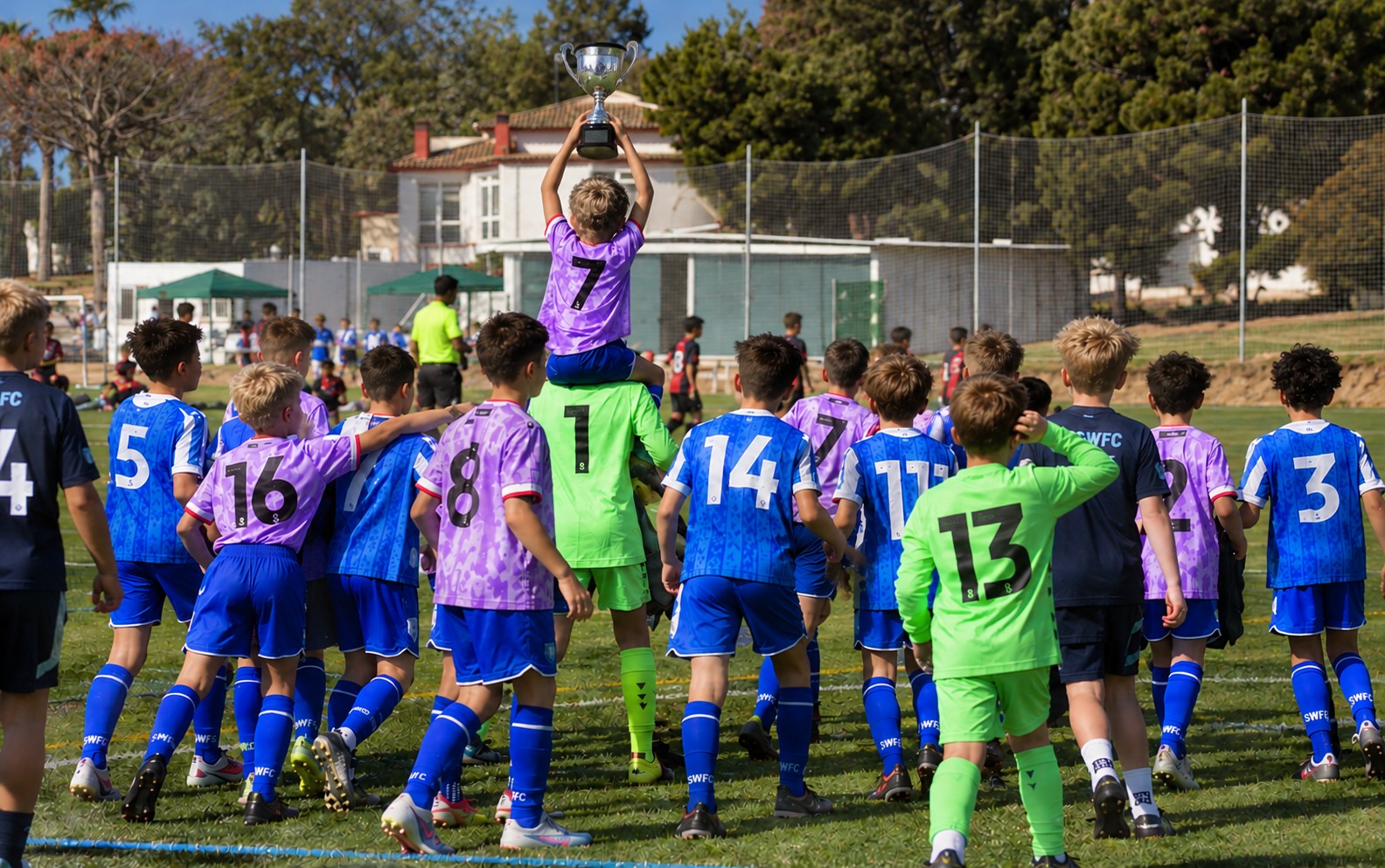 Junior players celebrating with a trophy raised above the team